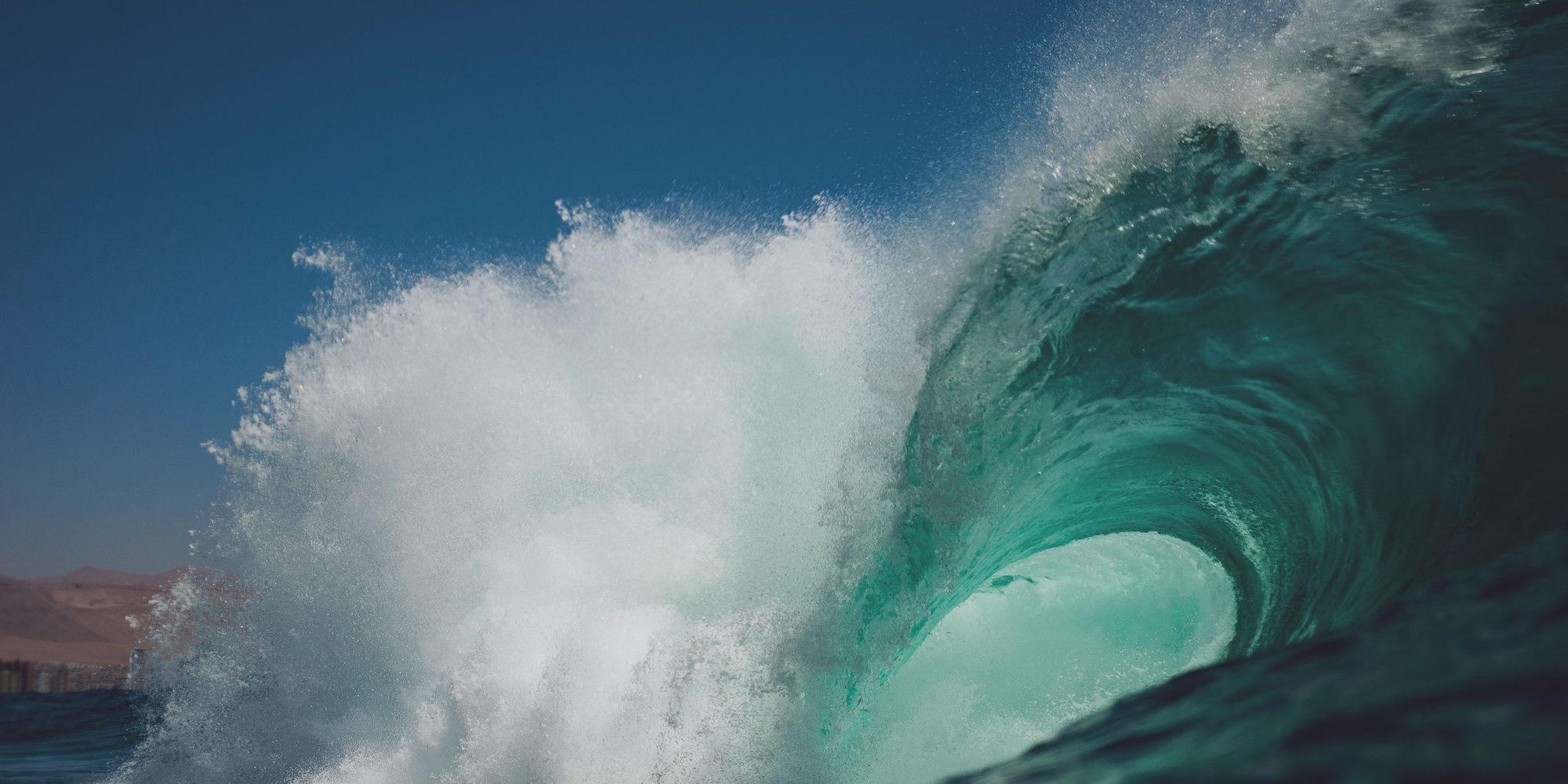 A glassy wave curling over in clear green water